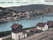 Reprodukce pohlednice zachycující levobřežní část davelské obce a část železniční stanice Davle. Spojnicí obce s nádražím byl v té době pouze ocelový most přes řeku stojící v pozadí. Most je znám především tím, že posloužil při natáčení válečného filmu Most u Remagenu.
