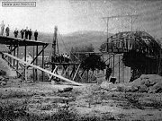 Rozestavn eleznin most pes eku Szavu v Tnci. V okamiku pozen snmku je ji dokonen kamenn pil i ob mostn opry na bezch eky. Zrove se ji stav jedno ocelov mostn pole, kter dodala firma Prask akciov strojrny. K dokonen prac na most dolo roku 1896.